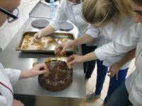 Zdjęcie przedstawiające uczniów dekorujących ciasto