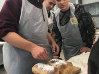 Zdjęcie przedstawiające uczniów i świeżo upieczony chleb